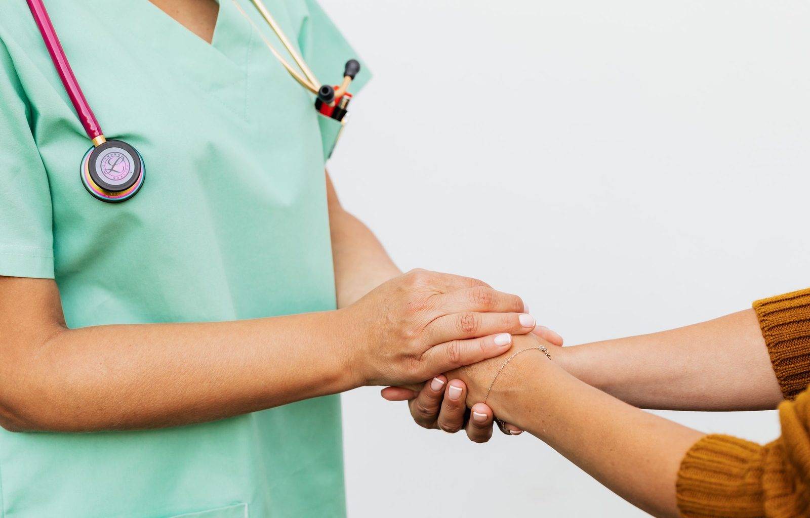 A provider holding a patient's hand across a wooden table